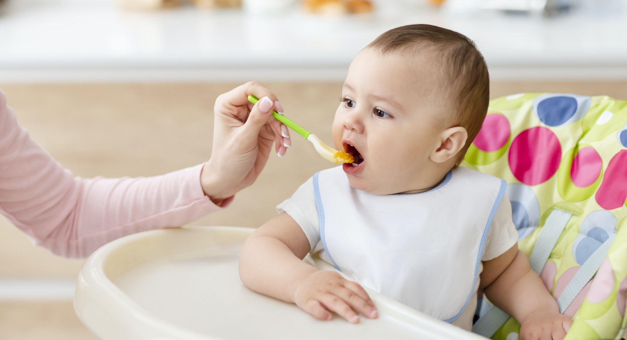 Mamă care hrănește un copil mic cu mâncare proaspătă